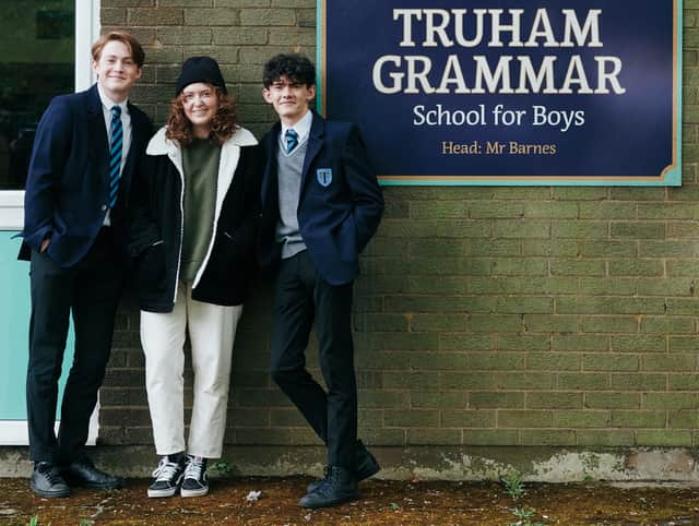 Kit Connor, Alice Oseman, and Joe Locke standing by the Truham Grammar School for Boys sign (Credit: Rob Youngson)