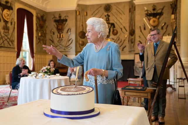 Queen Elizabeth II cuts a cake to celebrate the start of the Platinum Jubilee during a reception in the Ballroom of Sandringham House on 5 February (Photo: JOE GIDDENS/POOL/AFP via Getty Images)