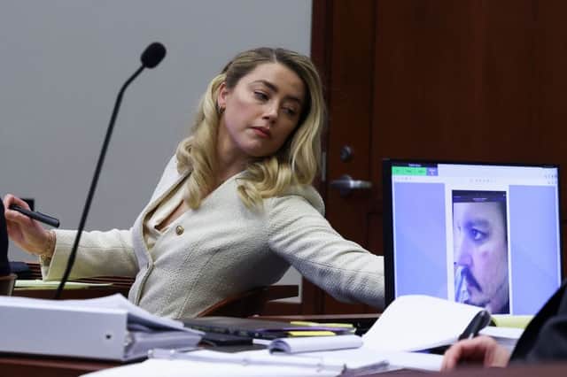 Amber Heard listening to ex-husband Johnny Depp, as a picture of an injury to his face is seen on a screen, during his defamation trial against her at the Fairfax County Circuit Courthouse (Photo: EVELYN HOCKSTEIN/POOL/AFP via Getty Images)