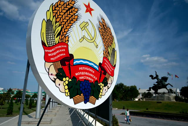A woman walks by the coat of arms of Transnistria in Tiraspol, 2021.