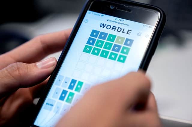 This photo illustration shows a person playing online word game Wordle on a mobile phone (Photo by STEFANI REYNOLDS/AFP via Getty Images)