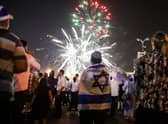 Israeli youths dressed in memorabilia depicting the Israeli flag watch fireworks over the centre of Jerusalem