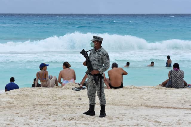 <p>A member of the newly created Tourist Security Battalion of the National Guard stands guard at a beach in Cancun (Photo: AFP via Getty Images)</p>