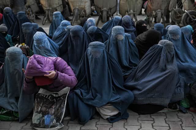 Women wearing a burqa wait for free bread in front of a bakery in Kabul on January 24, 2022. (Photo by Mohd RASFAN / AFP)