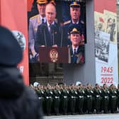 A screen shows Russian President Vladimir Putin giving a speech as servicemen line up on Red Square during the Victory Day military parade in central Moscow on May 9, 2022