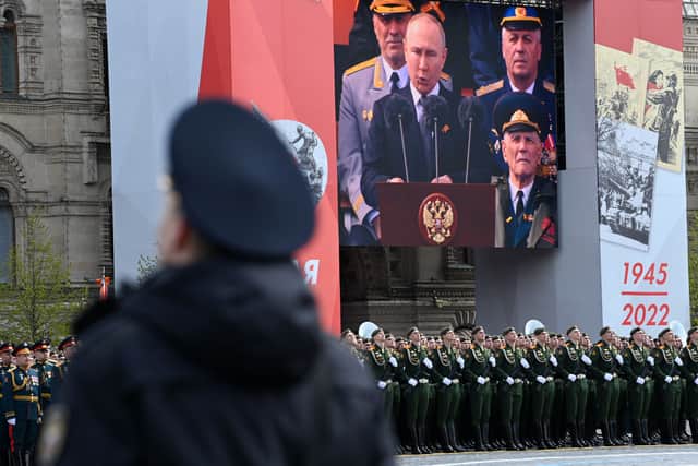 A screen shows Russian President Vladimir Putin giving a speech as servicemen line up on Red Square during the Victory Day military parade in central Moscow on May 9, 2022