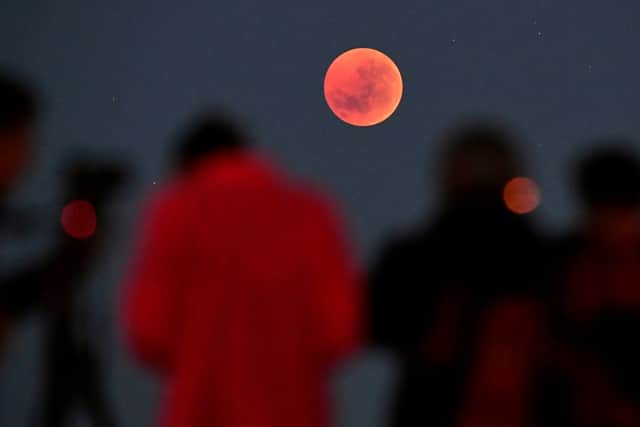 People gather to watch a “blood moon” eclipse in Melbourne on July 28, 2018 (Photo by WILLIAM WEST/AFP via Getty Images)