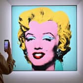 A woman takes a photo of Andy Warhol’s ‘Shot Sage Blue Marilyn’ during Christie’s 20th and 21st Century Art press preview at Christie’s New York on April 29, 2022 in New York City (Photo by ANGELA WEISS/AFP via Getty Images)