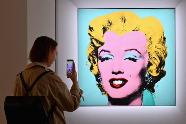 A woman takes a photo of Andy Warhol’s ‘Shot Sage Blue Marilyn’ during Christie’s 20th and 21st Century Art press preview at Christie’s New York on April 29, 2022 in New York City (Photo by ANGELA WEISS/AFP via Getty Images)