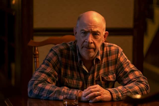 JK Simmons in Night Sky, wearing a flannel shirt and sat at a table with a concerned look (Credit: Chuck Hodes/Prime Video)