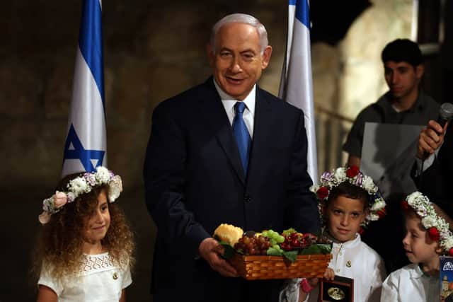 Former Israeli Prime Minister Benjamin Netanyahu holds a basket of fruit he received from local children in memory of the Biblical commandment for farmers to bring the “first fruits” (bikurim in Hebrew) to the Temple ahead of the holiday of Shavuot