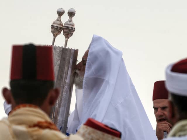 A Samaritan priest kisses the Torah scroll as worshippers gather to pray on top of Mount Gerizim, near the northern West Bank city of Nablus, at dawn on June 24, 2018 during celebrations of Shavuot