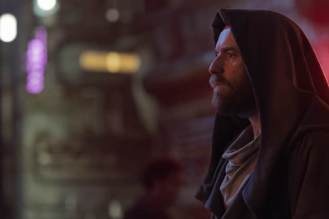 Ewan McGregor as Obi-Wan Kenobi, his hood pulled close to his face, hiding in a purple-lit street corner (Credit: Matt Kennedy/Lucasfilm)
