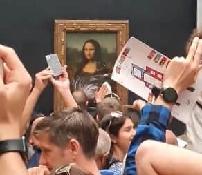 A man dressed as an elderly woman shocked visitors to the Louvre after smearing cake on the Mona Lisa. (Credit: PA)