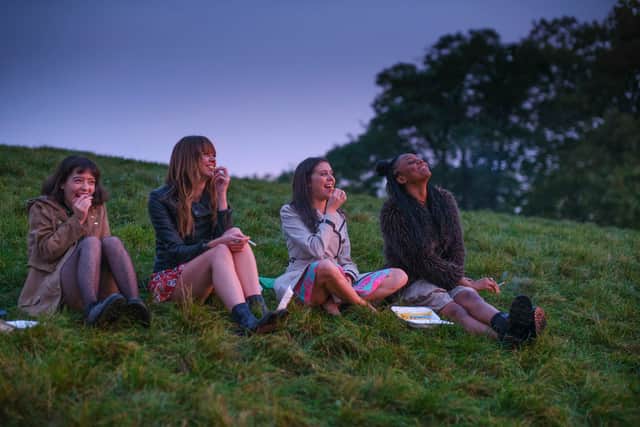 Marli Siu as Nell, Emma Appleton as Maggie, Bel Powley as Birdy, and Aliyah Odoffin as Amara, sat on the grass in the early hours of the morning (Credit: Matthew Squire/BBC/Universal International Studios)