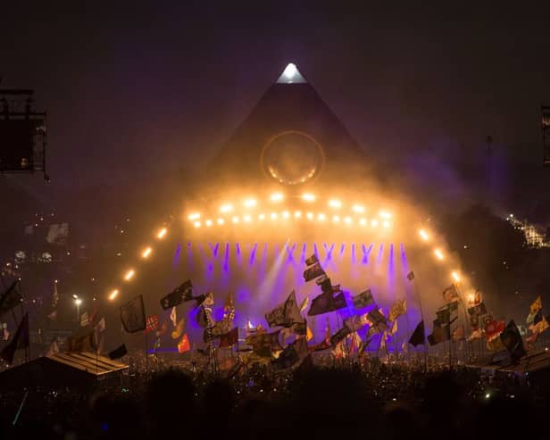 Revellers watch the Pyramid Stage at the Glastonbury Festival on June 29, 2019 (Photo by OLI SCARFF/AFP via Getty Images)