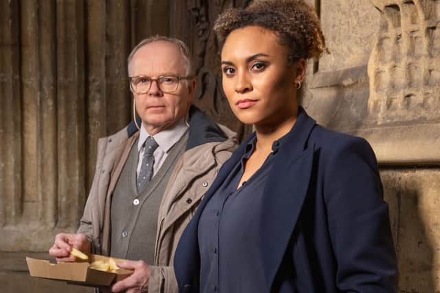 Jason Watkins as DS Dodds, holding a box of chips, and Tala Gouveia as DCI McDonald, both staring intently at the camera (Credit: ITV)
