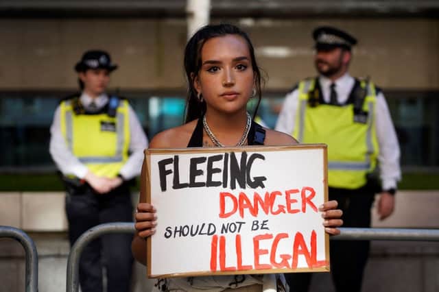 A protester holds a placard as she stands outside the Home Office in central London on 13 June to demonstrate against the UK government’s intention to deport asylum-seekers to Rwanda (Photo: NIKLAS HALLE’N/AFP via Getty Images)
