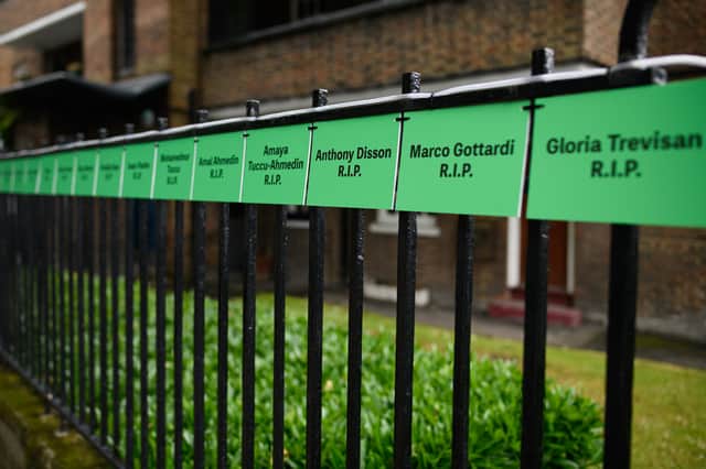 The names of some of the victims are seen on a railing near to the site of Grenfell Tower.