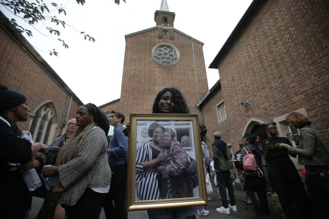 Relative Mary Mendy holds a picture of the late Mary Mendy (R) and Khadija Saye.