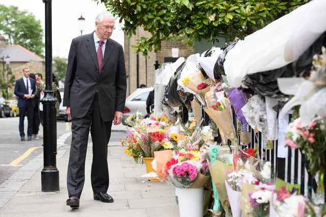  Sir Martin Moore-Bick looks at floral tributes after meeting local residents (Pic: Getty Images)