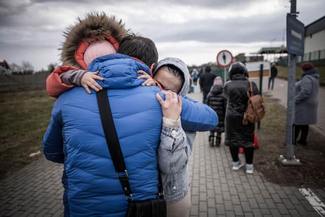 A man hugs his daughter and grandaughter after they crossed the border from Shehyni in Ukraine to Medyka in Poland