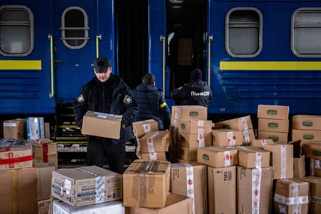Ukrainian police officers help volunteers to unload a train bringing international aid to Kyiv’s central railway station. (Credit: Getty Images)