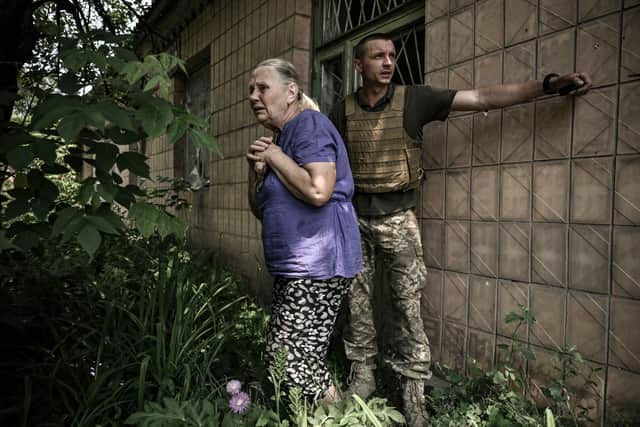 An elderly woman reacts as Ukrainian servicemen help her to take cover during an artillery duel between Ukrainian and Russian troops in the city of Lysychansk. (Credit: Getty Images)