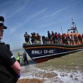 A police officer stands guard on the beach of Dungeness as RNLI members of staff help migrants to disembark from one of their lifeboat (Photo: BEN STANSALL/AFP via Getty Images)