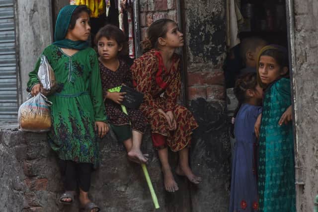 Children belonging to Afghan refugees living in Pakistan sit outside a shop on the outskirts of Lahore on June 19, 2022, on the eve of World Refugee Day (Photo by ARIF ALI/AFP via Getty Images)