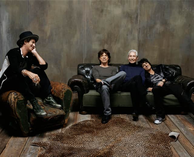 The Rolling Stones. Keith Richards is sat on an armchair, looking over fondly at his bandmates Mick Jagger, Charlie Watts, and Ronnie Wood, each sat on a sofa together (Credit: BBC/Mercury Studios/Steven Klein)