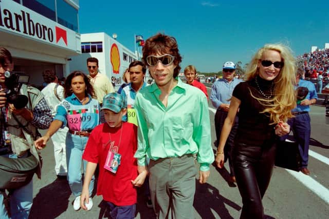 Mick Jagger, Jerry Hall and son James stroll in the pit area of the Estoril racetrack on September 24, 1995 (Photo by PATRICK KOVARIK/AFP via Getty Images)