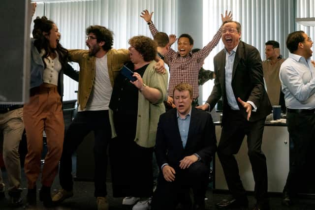 In a crowded office, one man has fallen to his knees in shock, while everyone around him celebrates (Credit: Netflix)