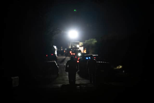 First responders walk toward the scene where a tractor-trailer was discovered with migrants inside outside San Antonio