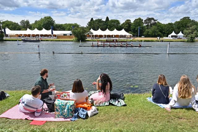 Spectators sit on the grass by the River Thames as they watch a race at the Henley Royal Regatta, 2022 (Pic: AFP via Getty Images)