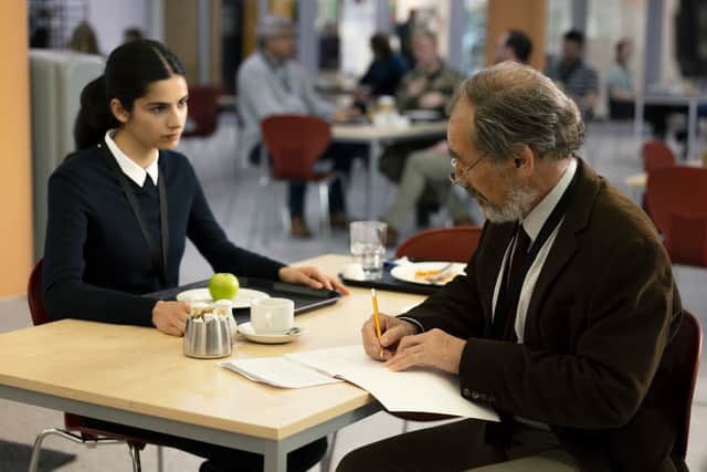 Hannah Khalique-Brown as Saara Parvin, sat across from Mark Rylance as John Yeabsley. She has a green apple on the plate in front of her, and he is writing in a notebook with a yellow pencil (Credit: Manuel Vazquez/Channel 4)
