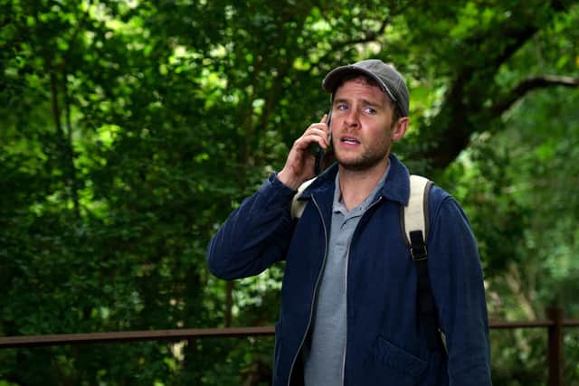 Iain De Caestecker as Gabe, standing in the woods and taking a phone call, looking anxious (Credit: Jamie Simpson/BBC/Hartswood Films)