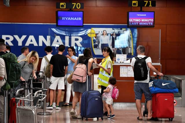 A Ryanair employee talks to a passenger at the check-in counters at the Terminal 2 of El Prat airport in Barcelona on July 1, 2022 (Photo by PAU BARRENA/AFP via Getty Images)