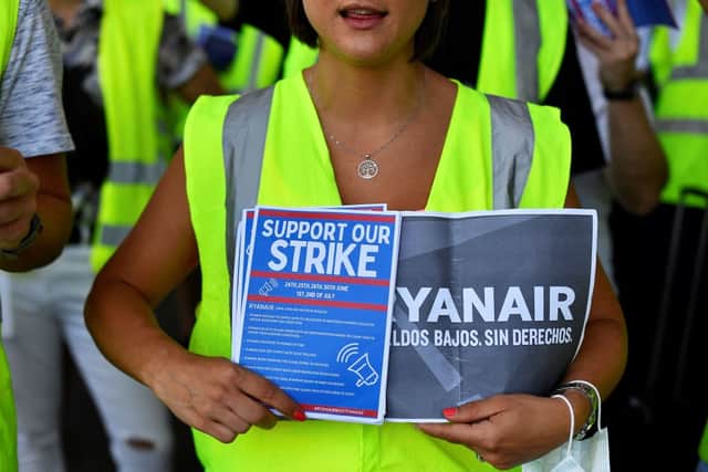 A Ryanair employee holds flyers reading “Support our strike” (Photo by PAU BARRENA/AFP via Getty Images)