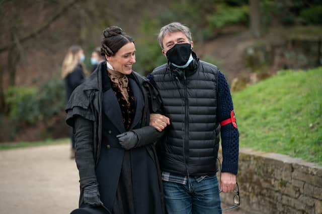 Suranne Jones in costume as Anne Lister, walking arm in arm with director Fergus O’Brien (Credit: BBC/Lookout Point/HBO/Aimee Spinks)