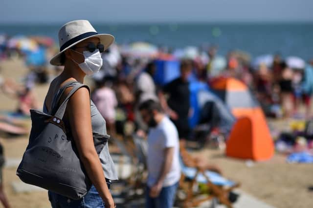A woman wearing a face mask arrives on the  beach in the sea in Southend on Sea, south east England, on June 24, 2020 (Photo by BEN STANSALL/AFP via Getty Images)