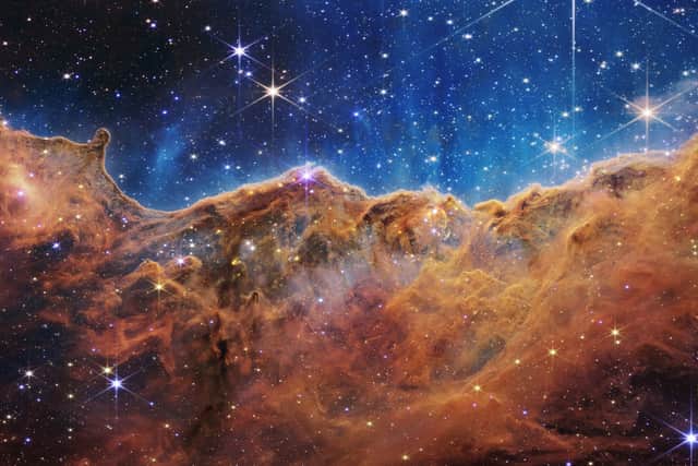 A landscape of mountains and valleys speckled with glittering stars is actually the edge of a nearby, young, star-forming region called NGC 3324 in the Carina Nebula (Image: NASA)