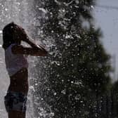 A woman cools off in a fountain in Sevilla. (Photo credit should read CRISTINA QUICLER/AFP via Getty Images)