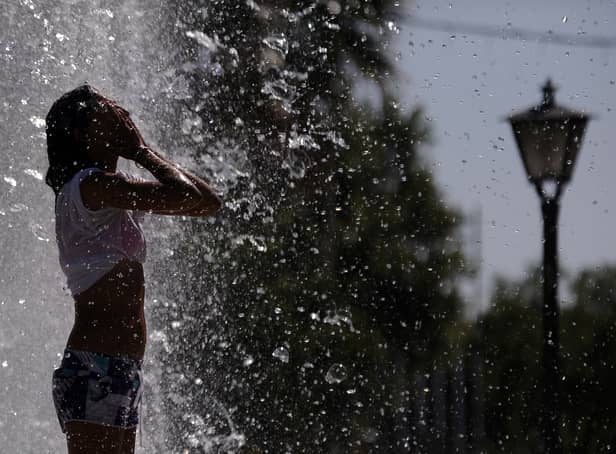 <p>A woman cools off in a fountain in Sevilla. (Photo credit should read CRISTINA QUICLER/AFP via Getty Images)</p>