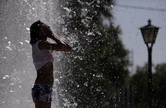 A woman cools off in a fountain in Sevilla. (Photo credit should read CRISTINA QUICLER/AFP via Getty Images)