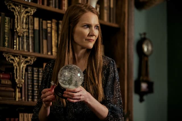 Darby Stanchfield as Nina Locke, stood next to a bookcase and holding a snowglobe (Credit: Amanda Matlovich/Netflix)