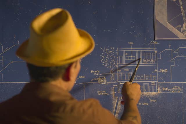 Fernando Araujo as Fernando Araujo, seen from behind wearing a yellow hat, gesturing at blue prints (Credit: Netflix)