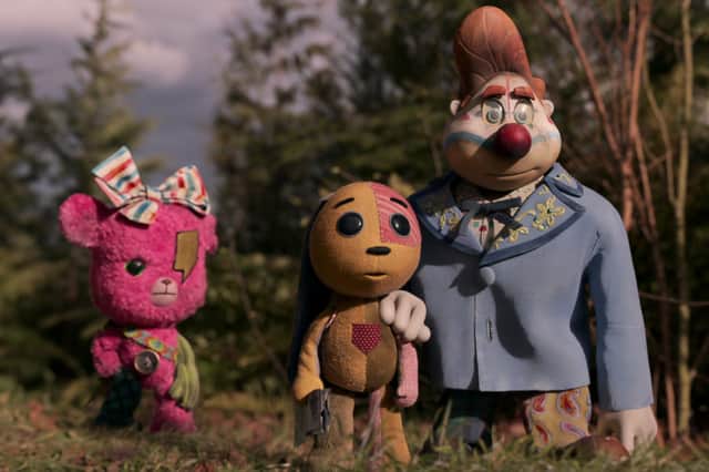 Stop motion models Rosy, a pink dog, Ollie, a patchwork dog, and Zozo, a larger clown, stand in a forest clearing (Credit: Netflix)