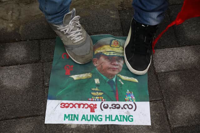 Myanmarese people stand on posters bearing the face of Myanmar military chief Min Aung Hlaing during a demonstration against the military coup (Photo by Chung Sung-Jun/Getty Images)