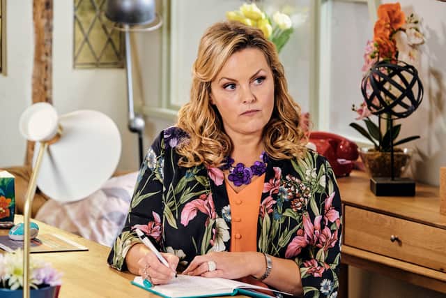 Jo Joyner in Shakespeare and Hathaway, wearing a floral jacket and writing in a notebook (Credit: BBC/Stuart Wood)